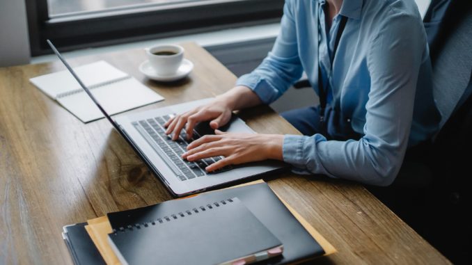 pexels-photo-5673496 person in blue long sleeve shirt using macbook pro on brown wooden table